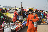 Kumbh Mela 2025: The Sacred Goes Viral. Walking Among the Food Stalls. A Pilgrim Near the Kumbh Mela Food Stalls. At the Maha Kumbh Mela, the streets are filled not only with pilgrims seeking spiritual solace but also with vibrant food stalls. A pilgrim walks past the bustling tents where food is prepared and sold to the thousands in attendance. These makeshift kitchens, run by fellow devotees, are a vital part of the festival’s communal experience, offering nourishment to those journeying through the sacred grounds. The aroma of freshly prepared food mingles with the sounds of the pilgrimage, highlighting the balance between material needs and spiritual devotion. As the pilgrim moves forward, they are reminded that sustenance, both spiritual and physical, is a shared experience at the Kumbh Mela.