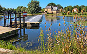 Flour mill and river Sarthe. Cyprien flour mill with a large wooden paddle wheel powered by the current of the Sarthe. Small lock, Village of Fillé-sur-Sarthe, Sarthe, Pays-de-la-Loire, France