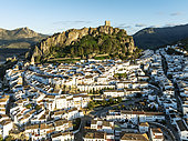 The White Town of Zahara de la Sierra below a Moorish castle. Aerial view. Drone shot. Cádiz province, Andalusia, Spain.