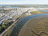 The town of Isla Cristina adjacent to the Carreras river with fishing boats and its marshland at low tide. Aerial view. Drone shot. Huelva province, Andalusia, Spain.