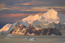 Icebergs and large fragments of drifting ice, here in the light of a summer evening, giant icebergs floating on the southern sea, climate melting global warming. Marguerite Bay, George VI Channel, Expedition below the Antarctic Circle
