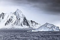 Iceberg and large fragments of drifting ice, here iceberg floating in front of the Antarctic Peninsula, climate melting global warming. Marguerite Bay, George VI Channel. Expedition below the South Polar Circle in Antarctica