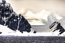 Iceberg et gros fragments de glace a la dérive, ici iceberg flottant devant un massif de la péninsule antarctique, climat fonte des glaces réchauffement climatique. Baie Marguerite, canal George VI. Expédition en dessous du cercle polaire sud en antarctique