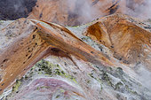 Colorful flanks of Hiyoriyama Mountain, Jigokudani geothermal site, Noboribetsu, Hokkaido Island, Japan. The geothermal site of Jigokudani, the Valley of Hell, offers a colorful, lunar landscape. Sulfur, volcanic gases and steam attack the rock.