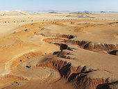 Canyons, arid plains grown with camelthorn trees (Vachellia erioloba) and isolated mountain ridges in the Tsondab Valley in the Namib Desert. Aerial view. Drone shot. Namibia.