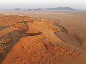 Sand dunes and isolated mountain ridges at the edge of the Namib Desert. Aerial view. Drone shot. Namibia.