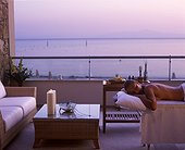 IN*Grèce, Paros, femme allongée sur table de massage sur balcon d'une suite de l'hôtel Asterias, mer au fond, coucher de soleil