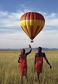 Kenya;Narok;Masai Mara - Two Maasai warriors watch a hot air balloon flight over Masai Mara.