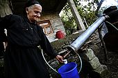 A smiling old woman distils raki, the traditional albanian spirit, near Permet, Albania