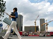 A Chinese young woman walks on a street as a building construction is seen in the background in the Central Business District (CBD) in Beijing.