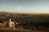 Man in traditional djellaba looks over the city of Fes at sunset, Fes, Morocco