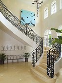 Elegant curving staircase with wrought iron banister railings in spacious hallway
