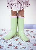 A girl standing on a table wearing spotty green boots