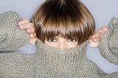 Close-up of a young woman covering her face in turtleneck
