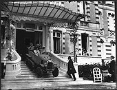 Employés de l'Hôtel Regina à Arcachon observant des clients sortir de celui-ci en autochenille type A en 1921.