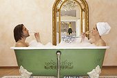 young couple sitting in bath drinking champagne, side view