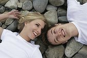Portrait of young couple lying on rocky beach