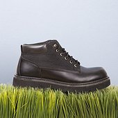 Studio shot of black leather shoe resting on grass.