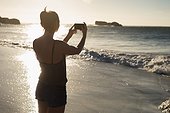 Female volleyball player taking photo with mobile phone on the beach